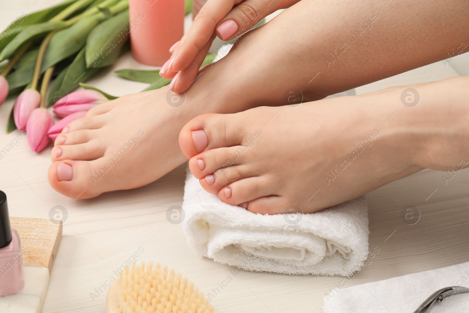 Photo of Woman with neat toenails after pedicure procedure on white wooden floor, closeup