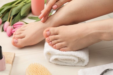 Photo of Woman with neat toenails after pedicure procedure on white wooden floor, closeup