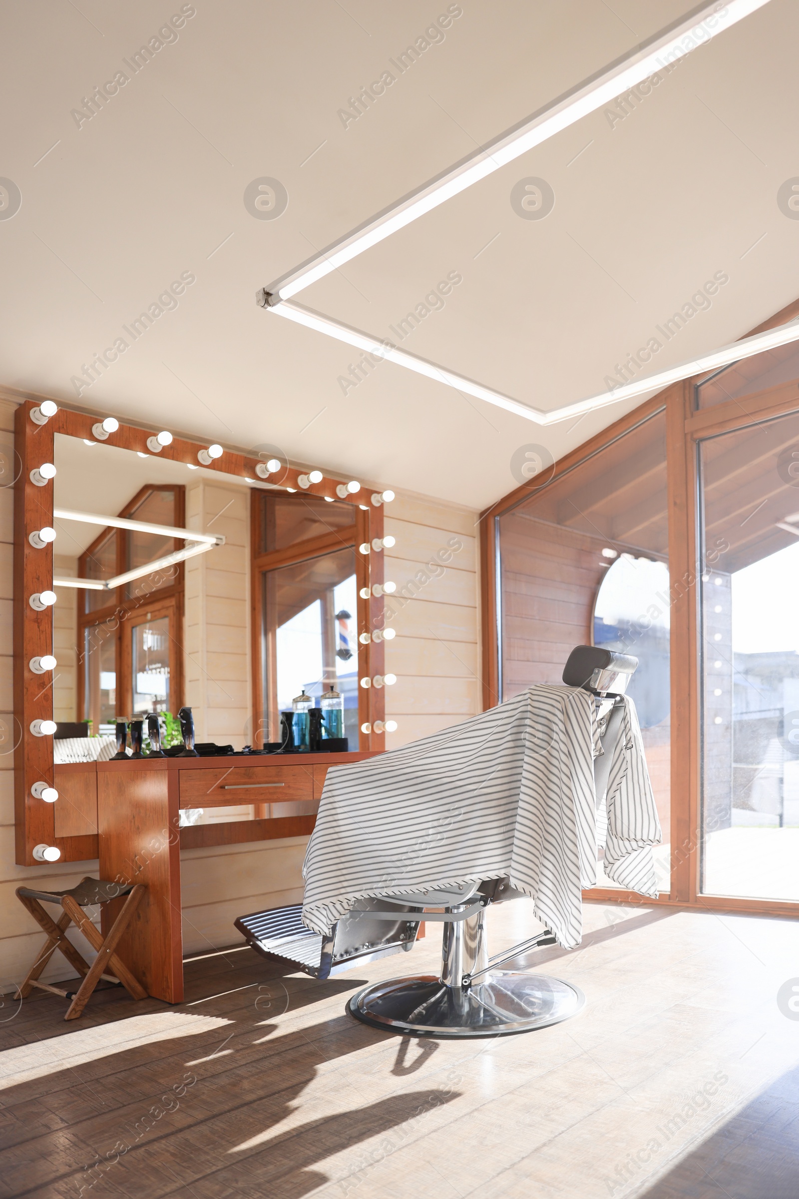 Photo of Stylish hairdresser's workplace with professional armchair and large mirror in barbershop. Interior design