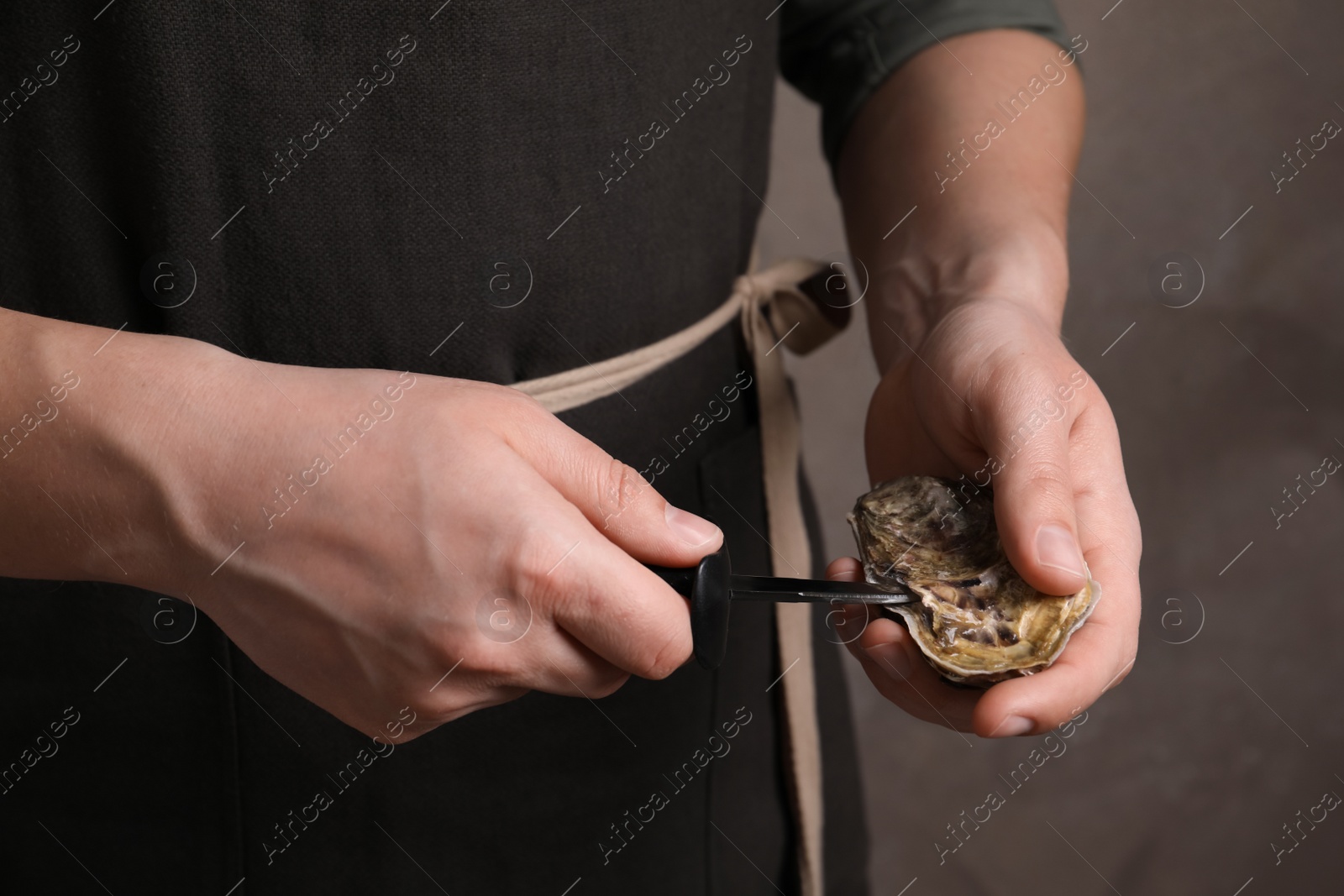 Photo of Man opening fresh oyster with knife, closeup