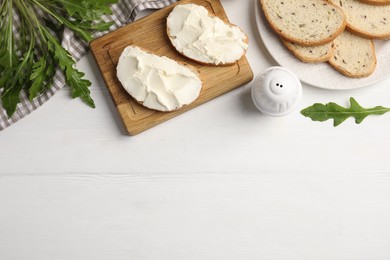 Photo of Bread with cream cheese on white wooden table, flat lay. Space for text