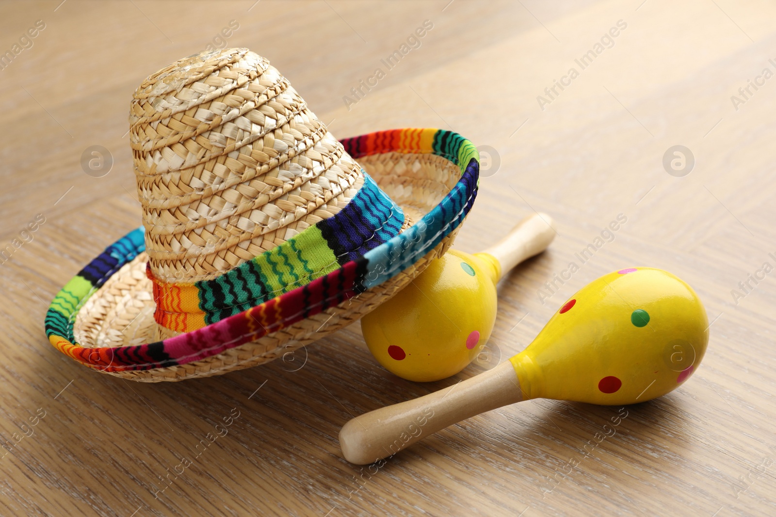 Photo of Mexican sombrero hat and maracas on wooden table