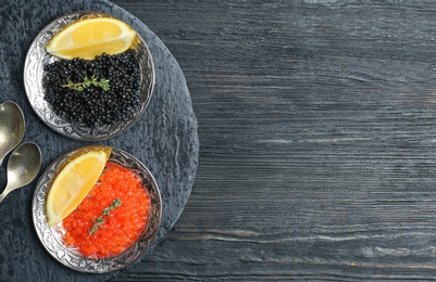 Photo of Plates with black and red caviar on wooden background