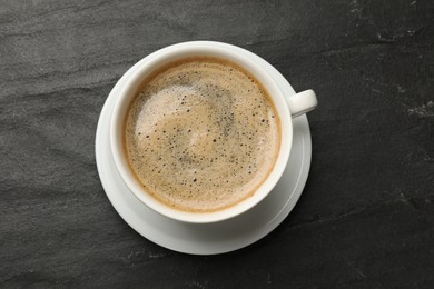 Cup of aromatic coffee on black table, top view