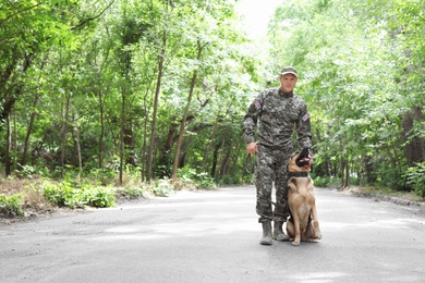 Man in military uniform with German shepherd dog, outdoors