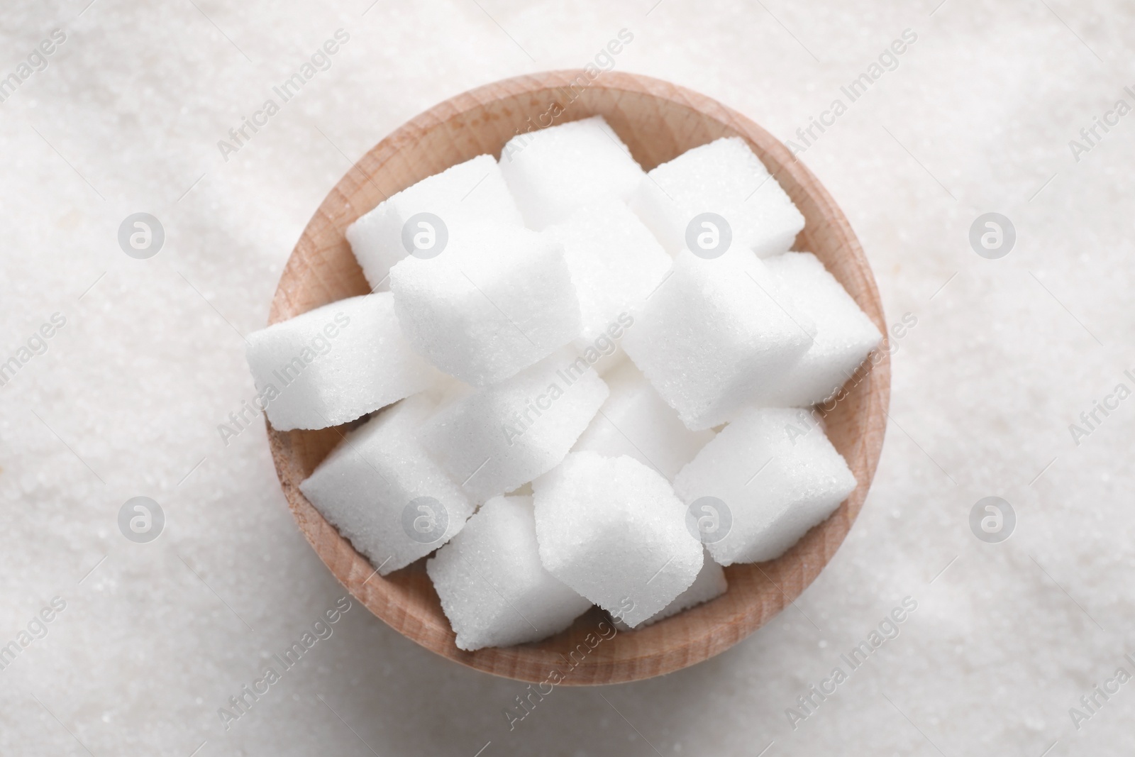 Photo of Different types of white sugar and bowl as background, top view