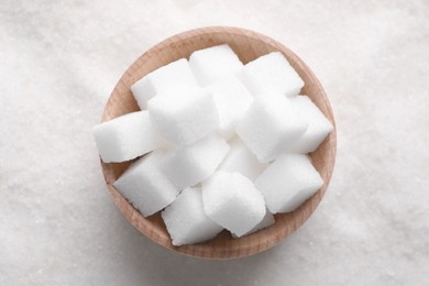 Different types of white sugar and bowl as background, top view