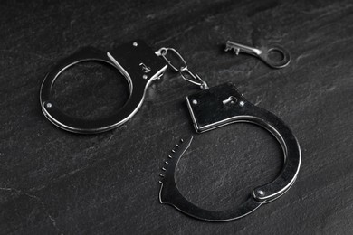 Photo of Classic chain handcuffs with key on black table