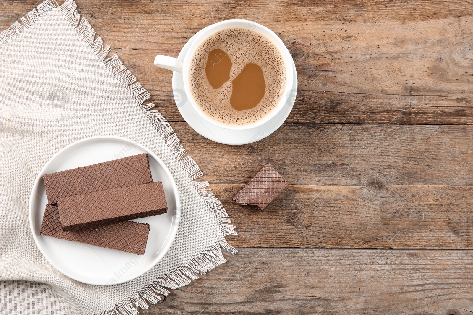 Photo of Plate of delicious chocolate wafers with cup of coffee on brown wooden background, top view. Space for text