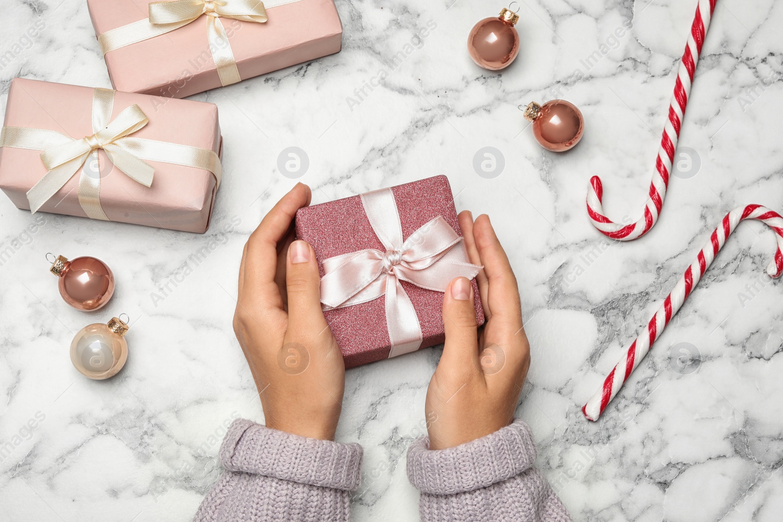 Photo of Young woman holding Christmas gift on white marble background, flat lay