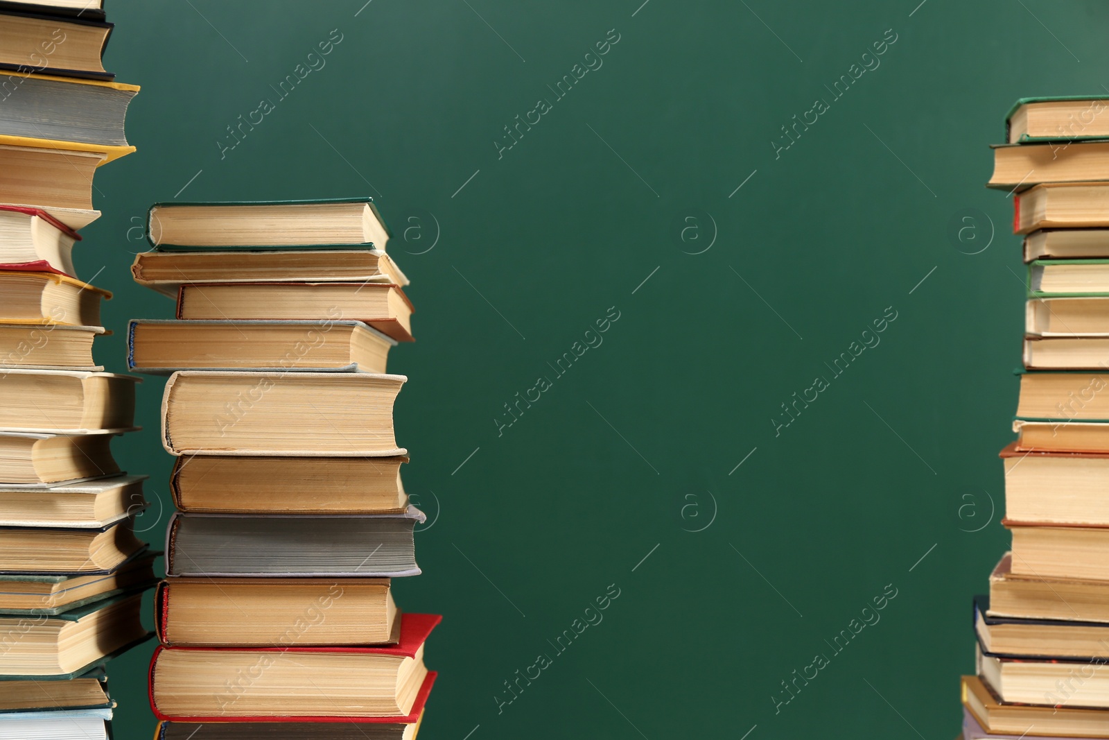 Photo of Many hardcover books near green chalkboard, space for text. Library material