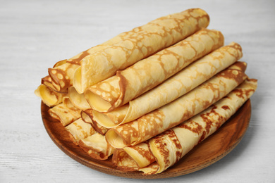 Photo of Fresh thin pancakes on white wooden table