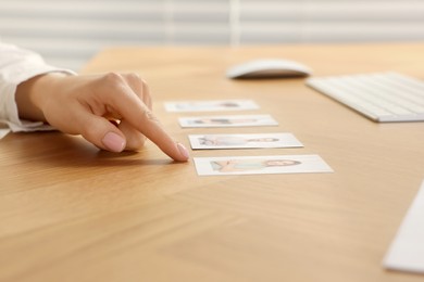 Photo of Human resources manager choosing employee among different applicants at wooden table, closeup