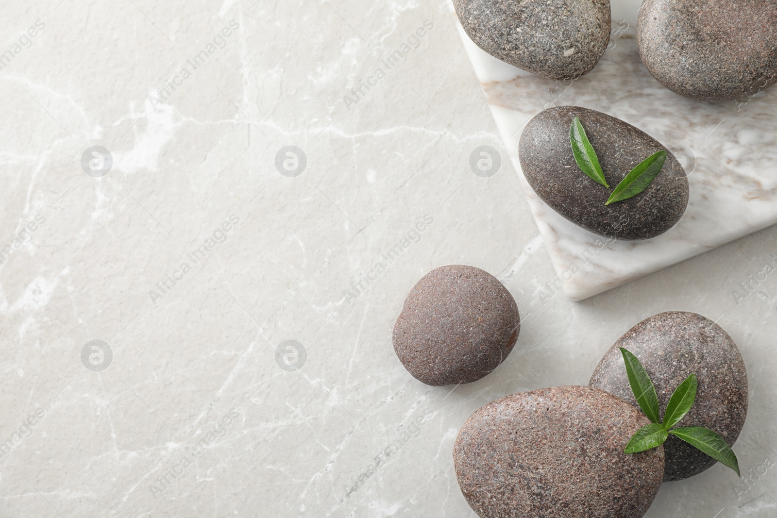 Photo of Flat lay composition with spa stones and green leaves on grey table, space for text