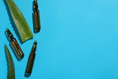 Photo of Pharmaceutical ampoules with medication and aloe leaves on light blue background, flat lay. Space for text