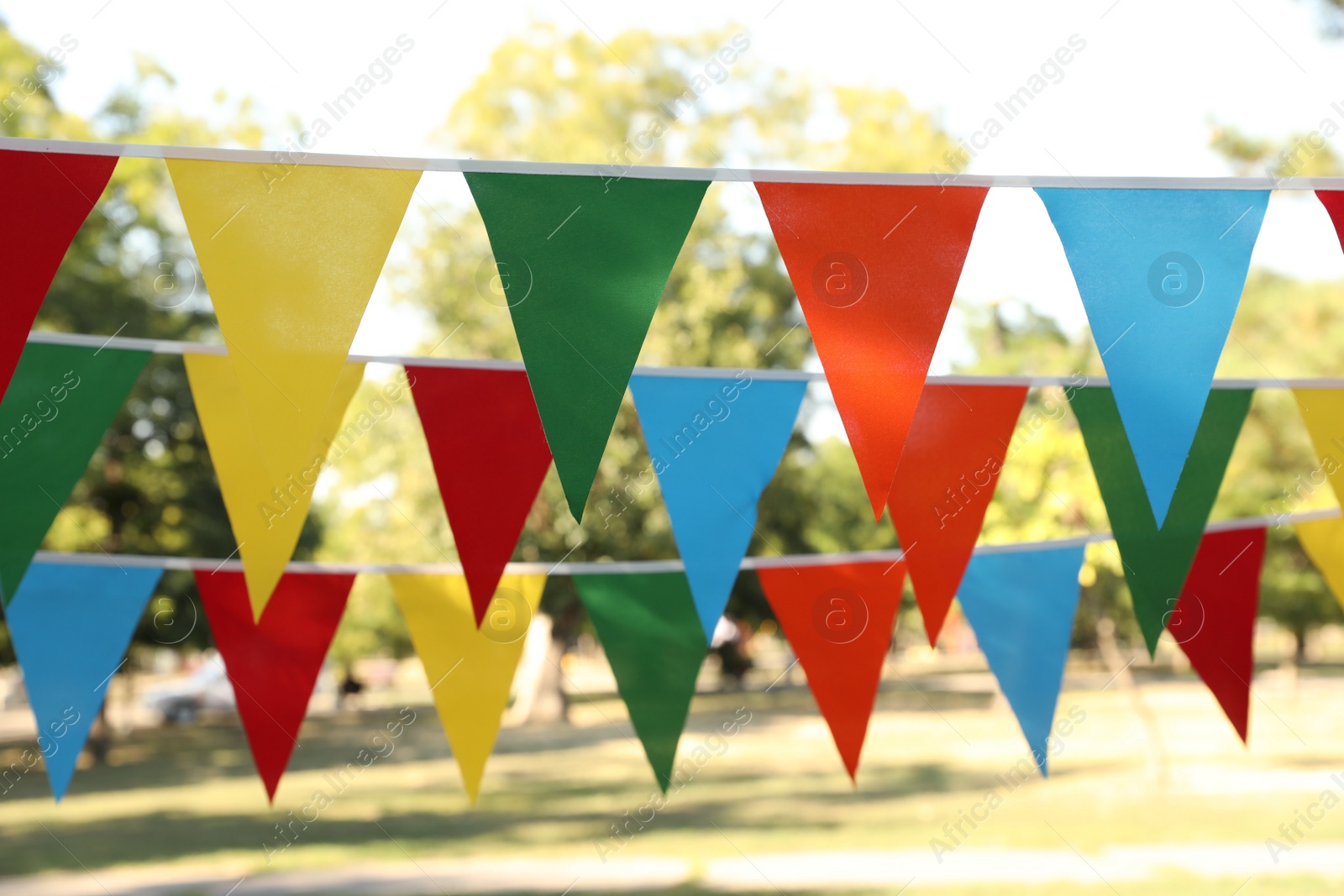 Photo of Colorful bunting flags in park. Party decor