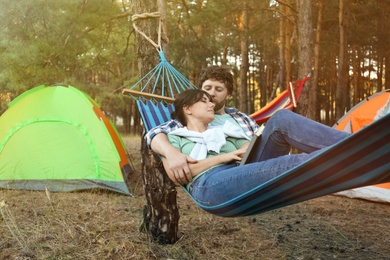 Photo of Lovely couple with book resting in comfortable hammock outdoors