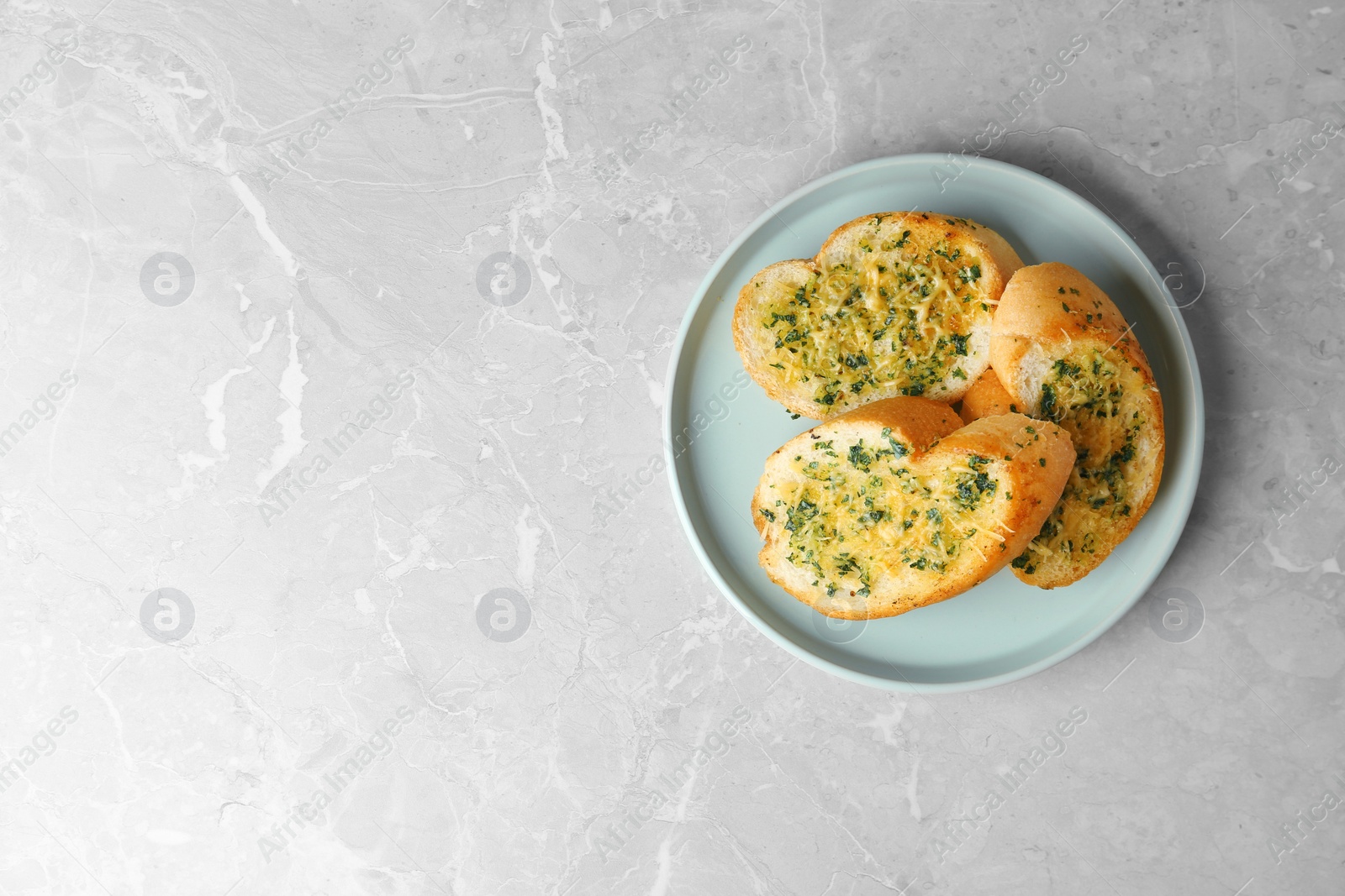 Photo of Slices of toasted bread with garlic, cheese and herbs on grey table, top view. Space for text