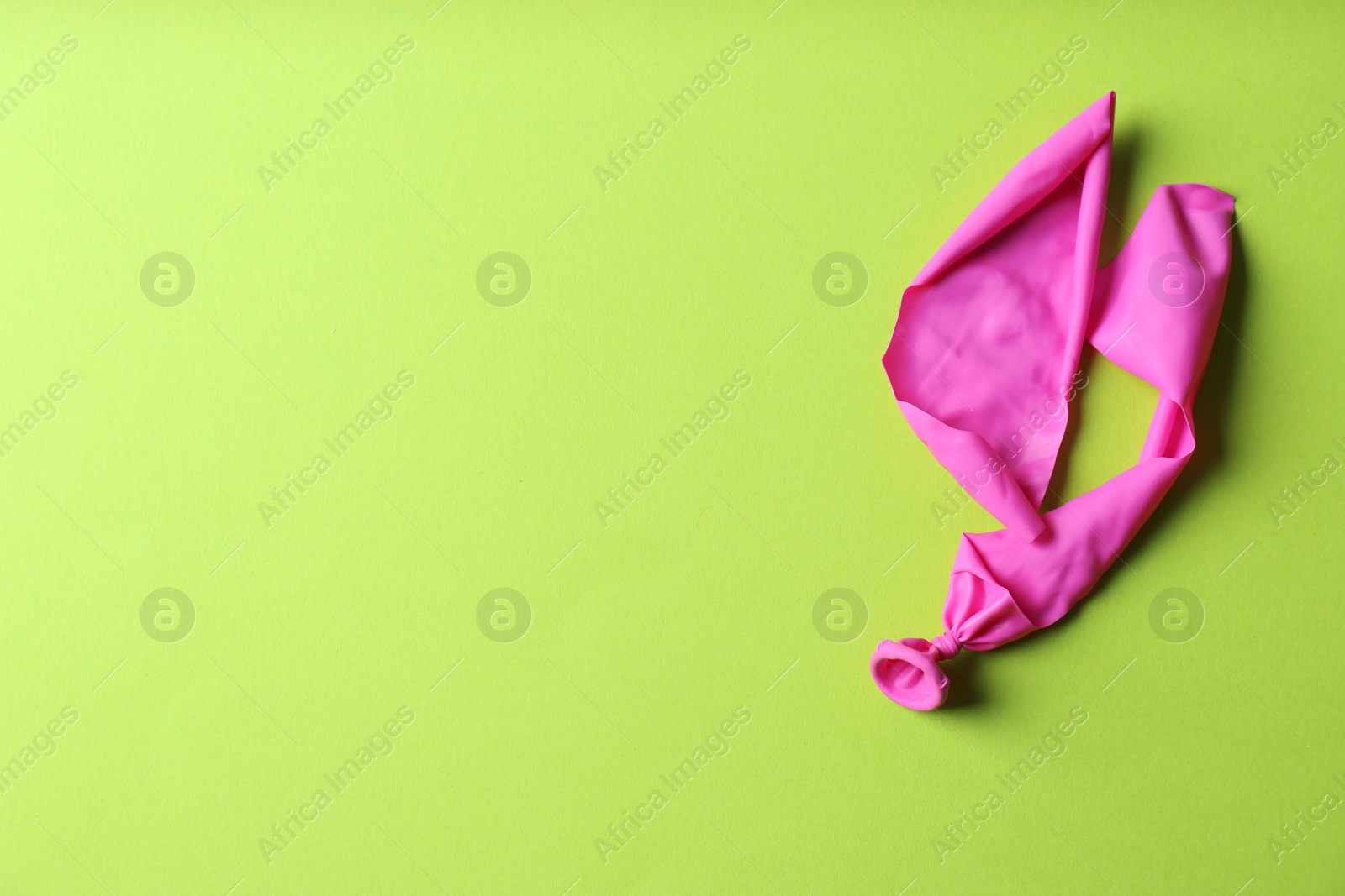 Photo of Popped balloon on color background, top view with space for text