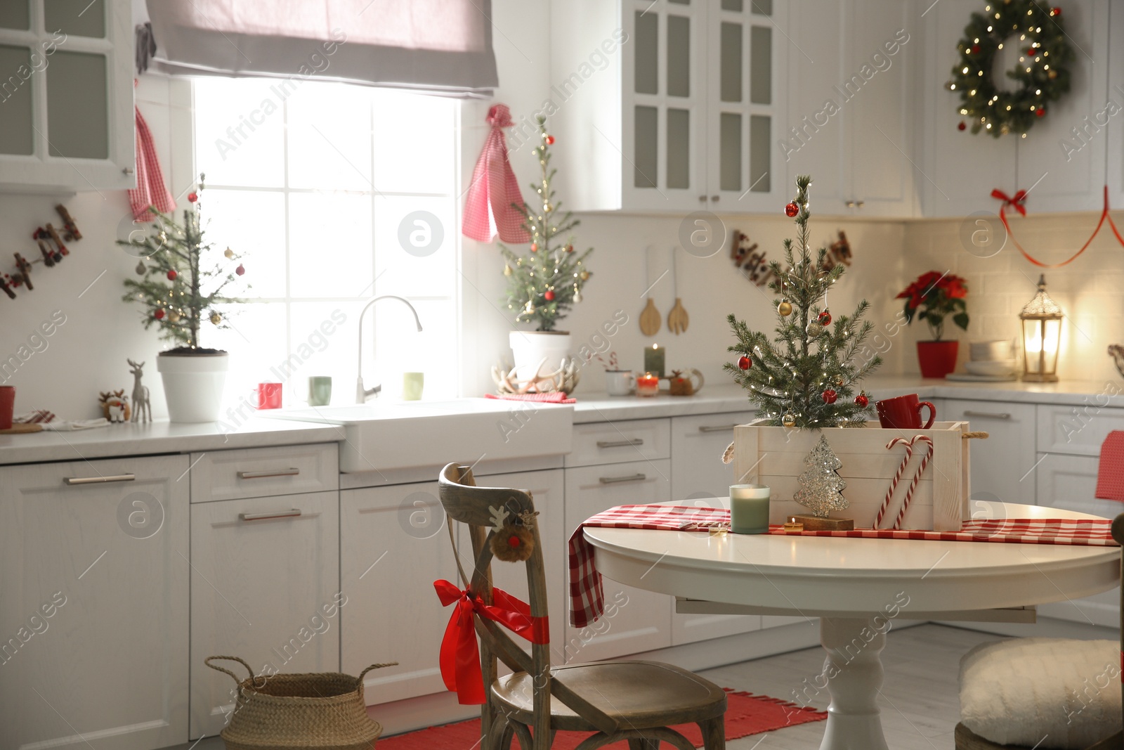 Photo of Small Christmas trees and festive decor in kitchen