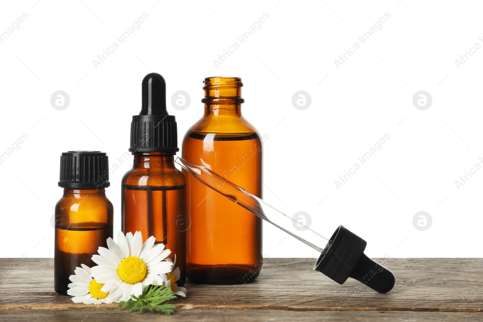 Photo of Chamomile flowers and cosmetic bottles of essential oil on wooden table against white background. Space for text