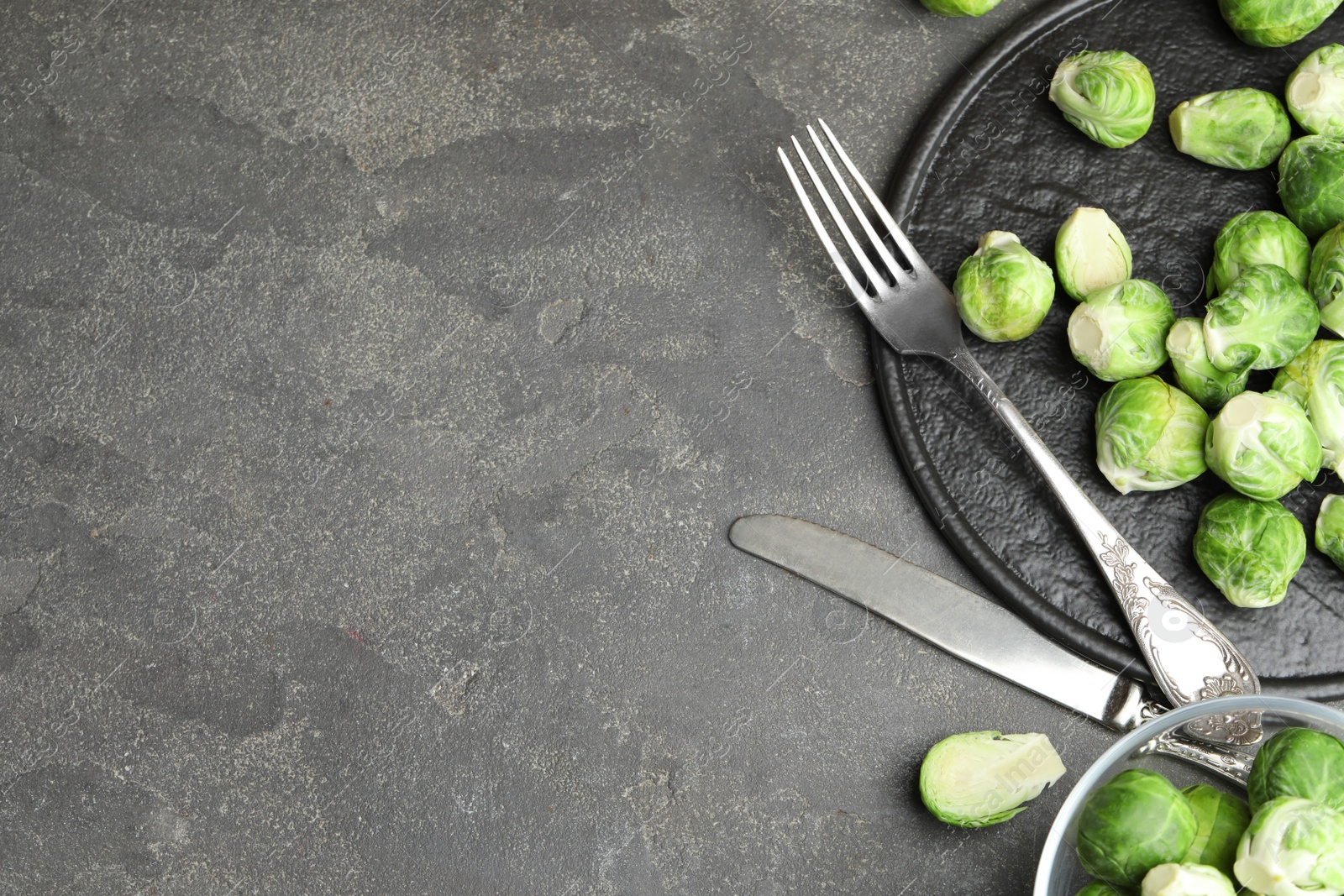 Photo of Fresh Brussels sprouts on grey table, flat lay. Space for text