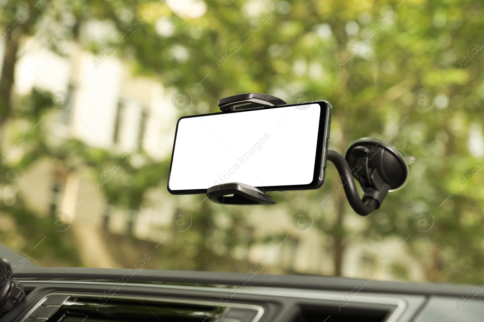 Photo of Car holder with modern mobile phone on windshield of automobile. Mockup for design