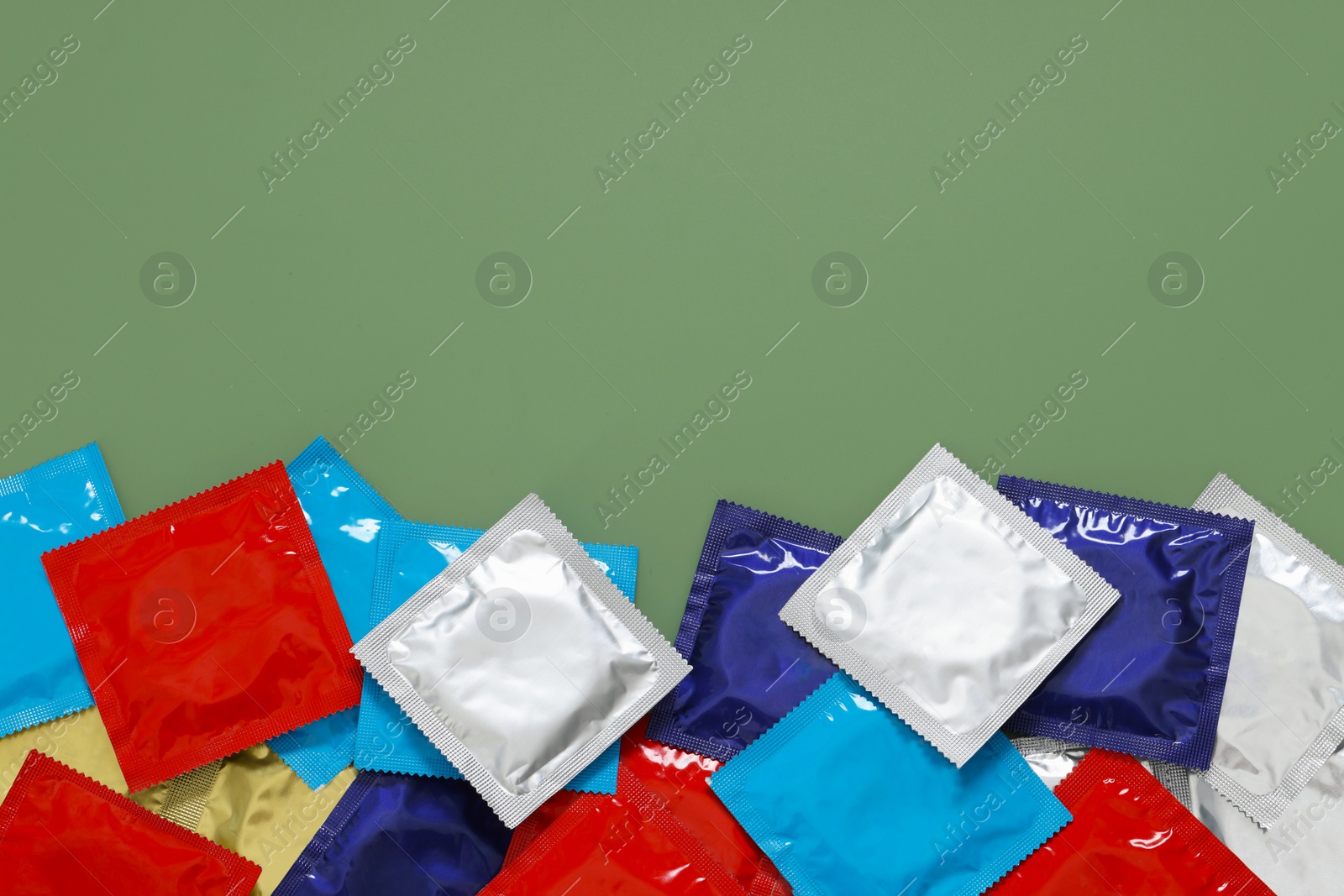 Photo of Packaged condoms on light green background, top view with space for text. Safe sex
