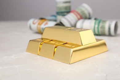 Photo of Shiny gold bars and dollar rolls on table