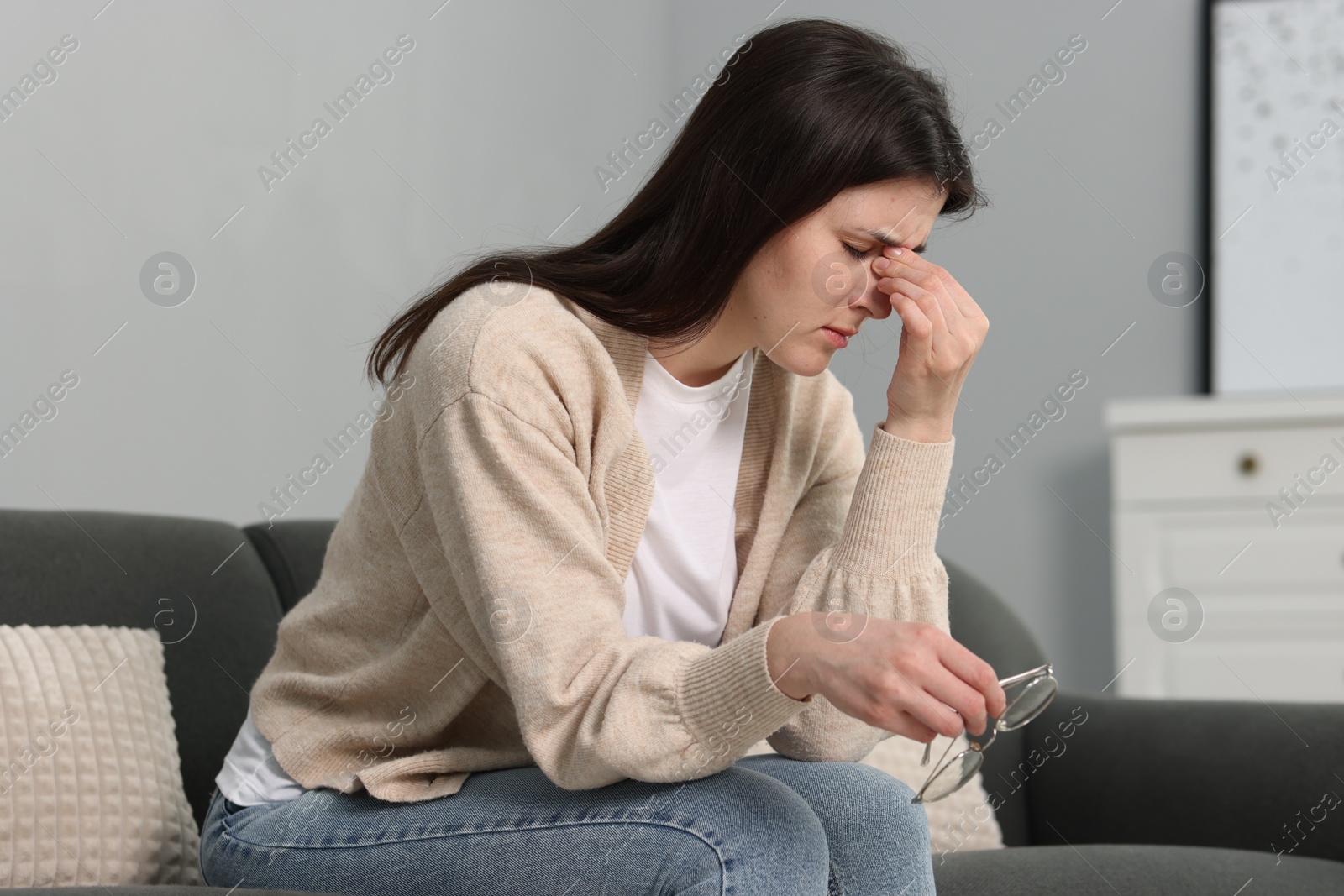 Photo of Overwhelmed woman sitting on sofa at home