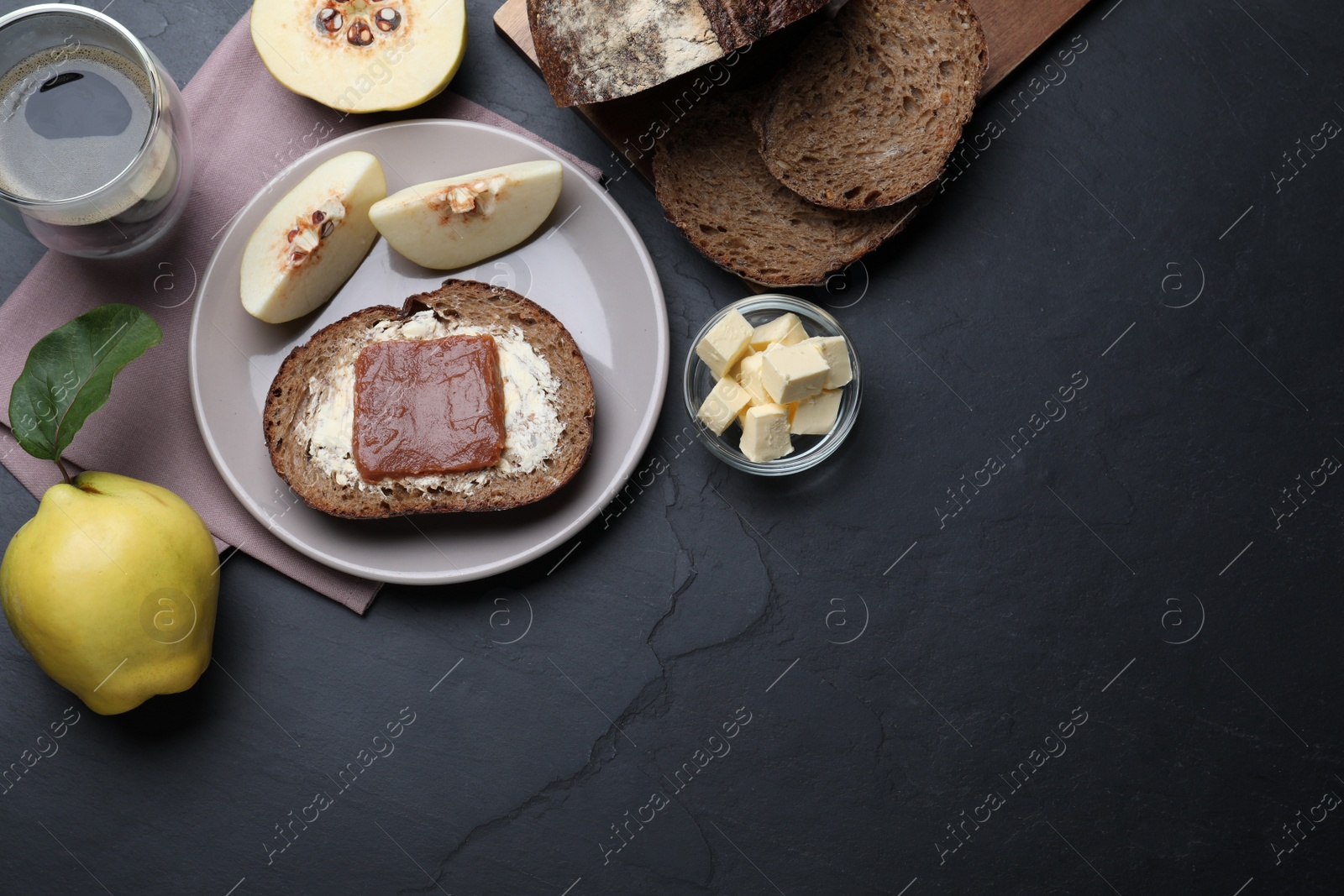 Photo of Bread with butter and quince paste served on black table, flat lay. Space for text