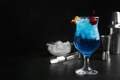 Photo of Glass of fresh cocktail on black table, space for text