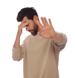 Embarrassed man covering face with hand on white background