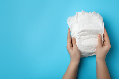 Photo of Woman with diapers on light blue background, closeup. Space for text