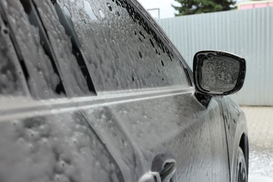 Photo of Auto with cleaning foam at car wash, closeup