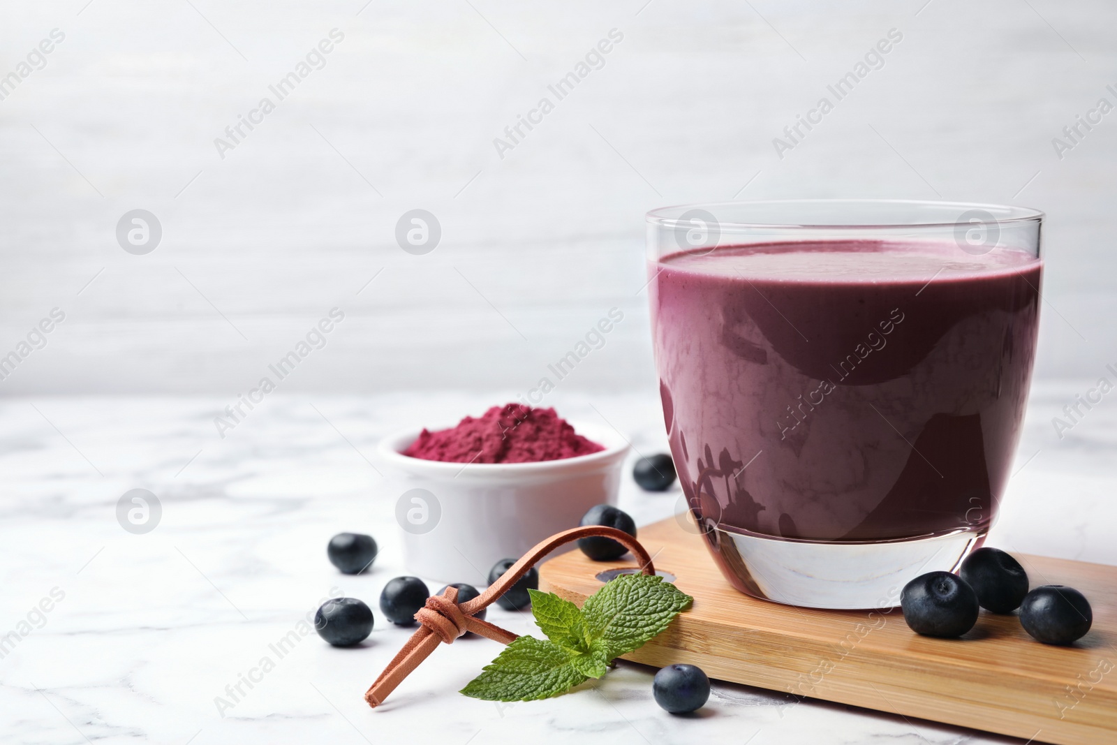 Photo of Tasty acai drink, powder and berries on marble table. Space for text