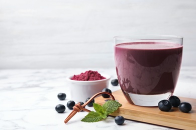 Tasty acai drink, powder and berries on marble table. Space for text