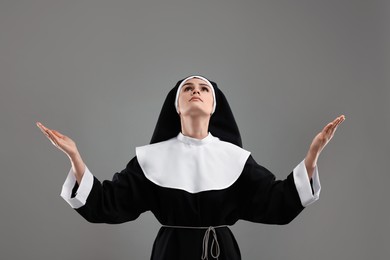 Nun praying to God on grey background