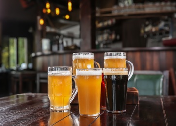Photo of Glasses of tasty beer on wooden table in bar