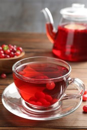 Tasty hot cranberry tea in glass cup and fresh berries on wooden table