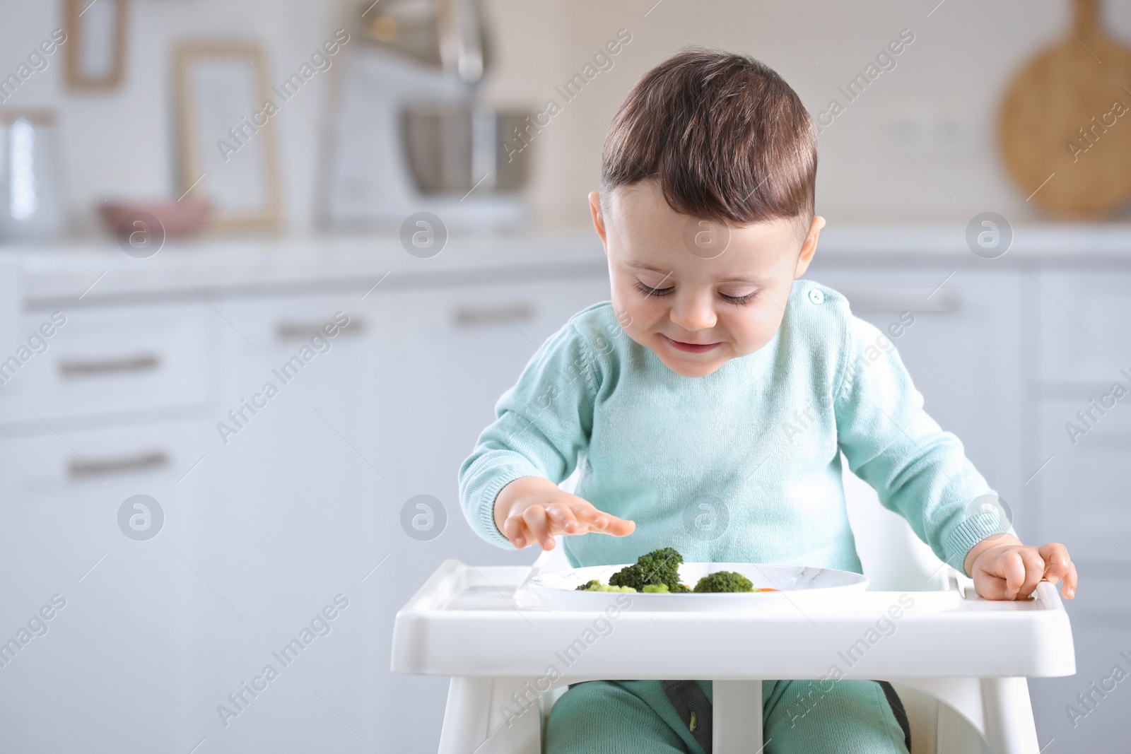 Photo of Cute little baby eating healthy food in high chair at home. Space for text