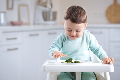 Photo of Cute little baby eating healthy food in high chair at home. Space for text