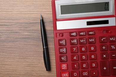 Photo of Calculator and pen on wooden table, top view. Space for text