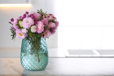 Photo of Vase with beautiful chrysanthemum flowers on table in kitchen, space for text. Interior design