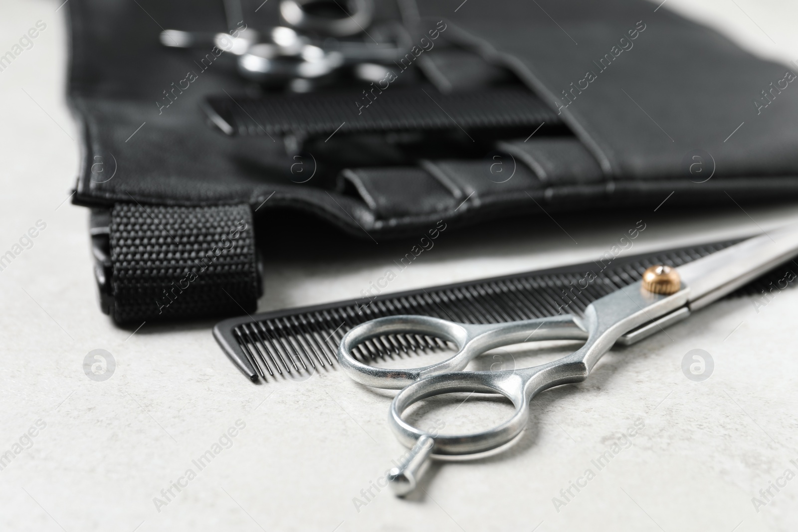 Photo of Hairdresser tools. Professional scissors, combs and leather organizer on white table, closeup