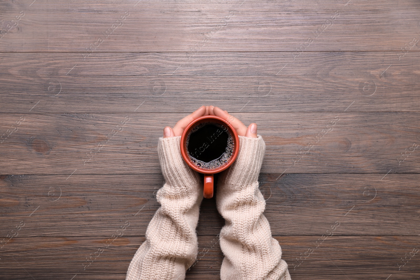 Photo of Woman with cup of coffee at wooden table, top view. Space for text