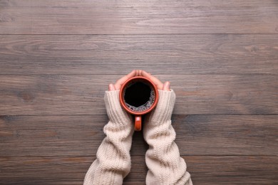 Photo of Woman with cup of coffee at wooden table, top view. Space for text