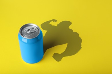 Energy drink and shadow in shape of sportsman's silhouette on yellow background 