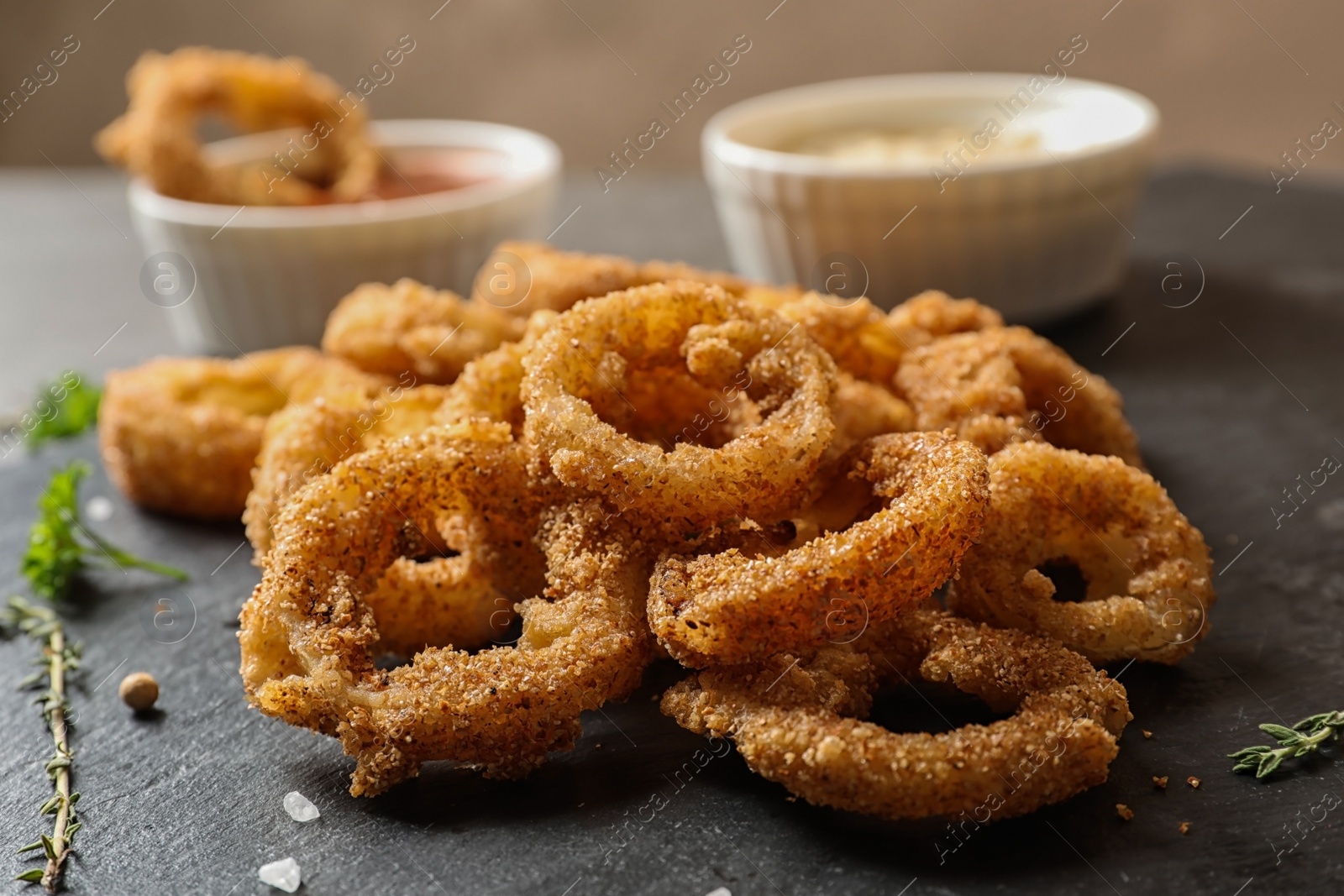 Photo of Homemade crunchy fried onion rings on slate plate, closeup