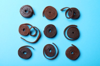 Photo of Delicious fruit leather rolls on light blue background, flat lay